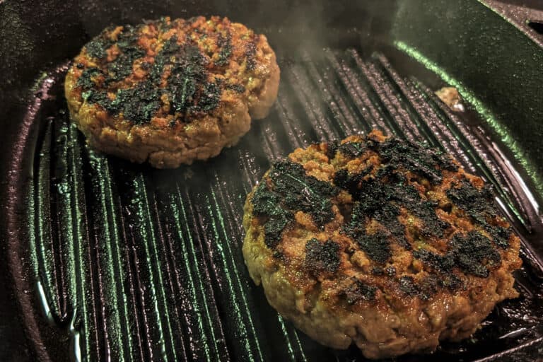 BBQ burger patties cooking on a cast iron grill pan