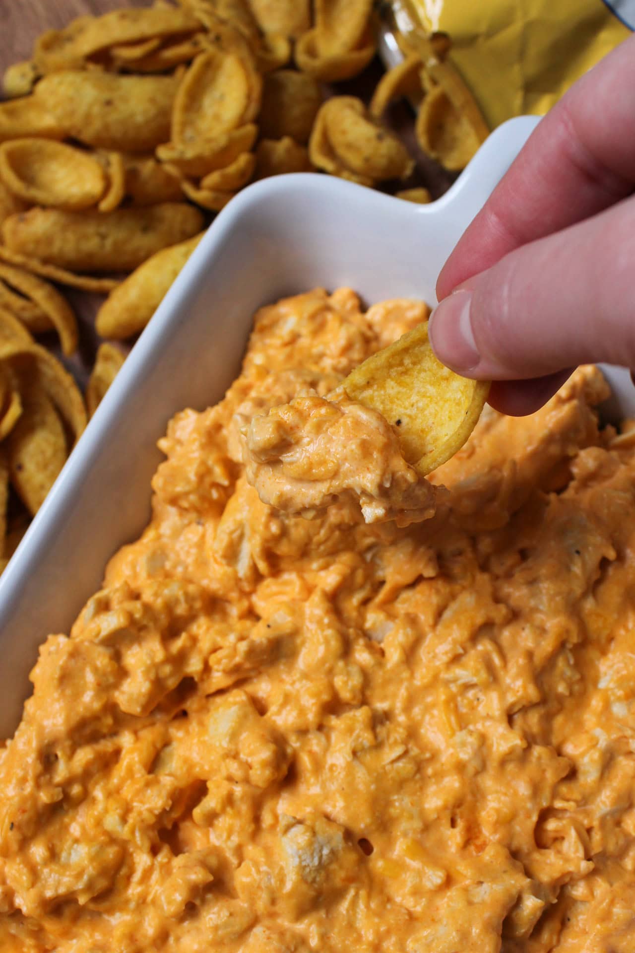 Oven baked buffalo chicken dip being scooped up by a frito.