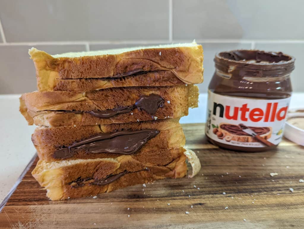 Four pieces of Nutella stuffed brioche bread stacked on a cutting board