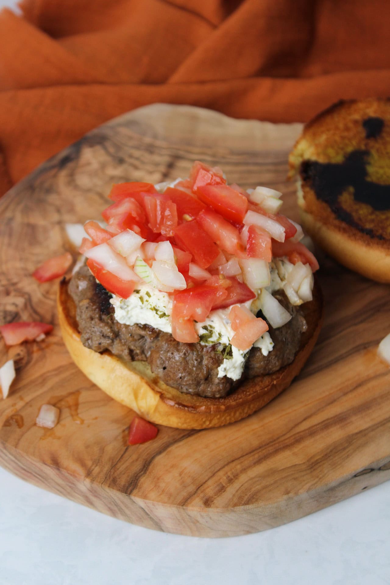 A burger topped with fresh tomato bruschetta.