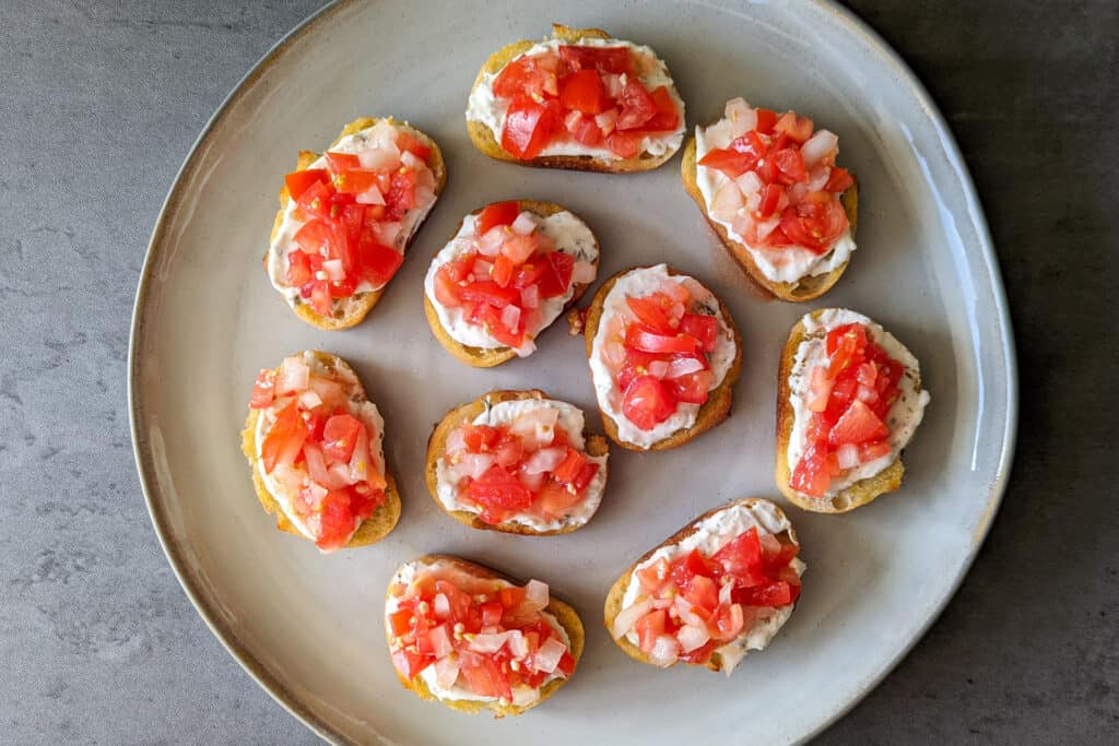 A plate of crostini topped with cheese and bruschetta
