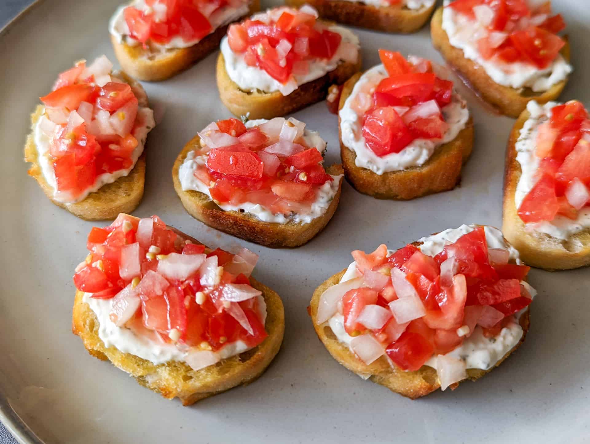 Fresh bruschetta topped crostini with cheese on a plate