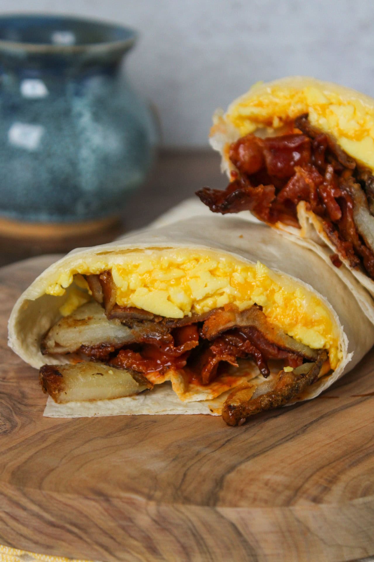 Potato bacon egg and cheese breakfast wrap cut in half.