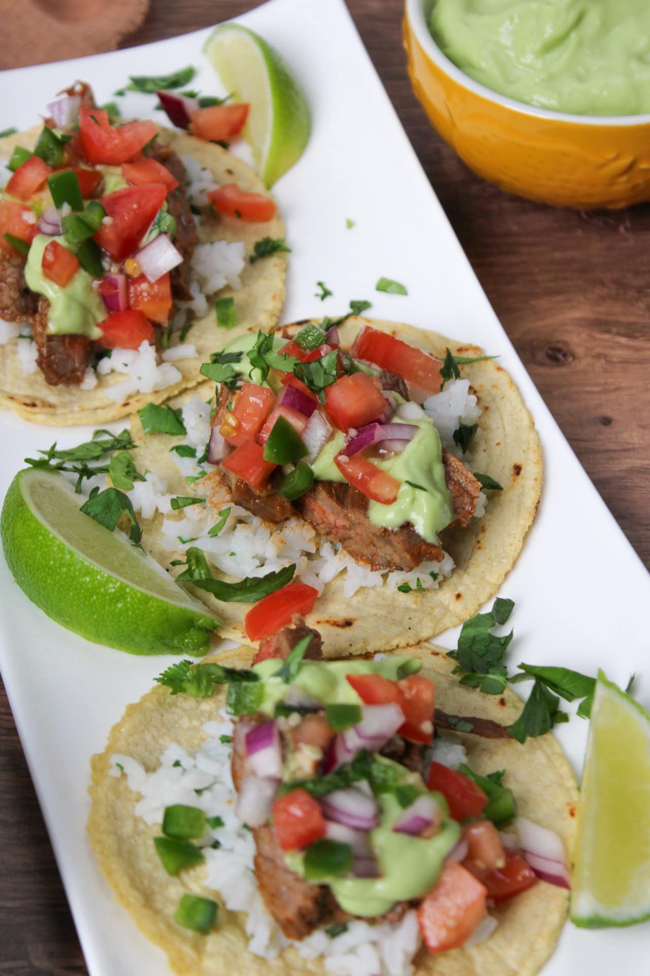 Carne asada street tacos topped avocado crema and pico de gallo.