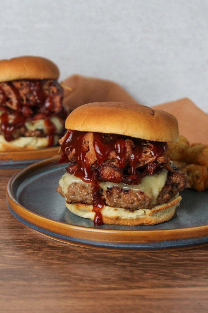 A burger topped with barbecue pulled pork and bacon.