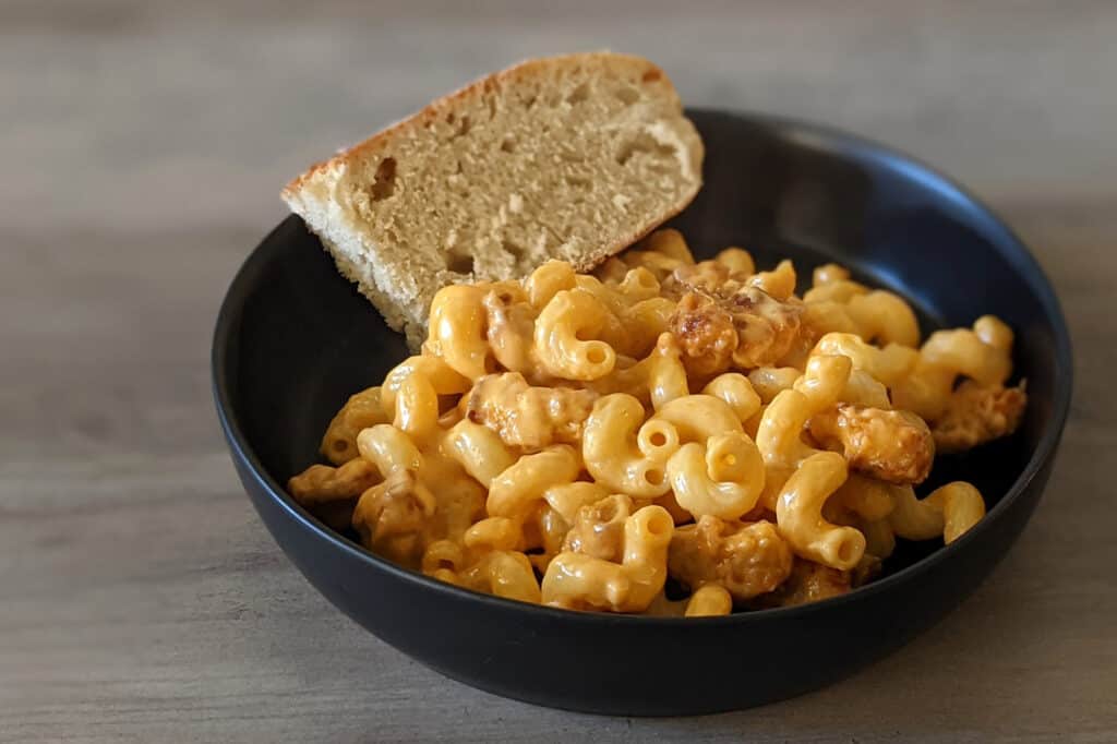 A bowl of buffalo chicken mac n cheese with a side of bread