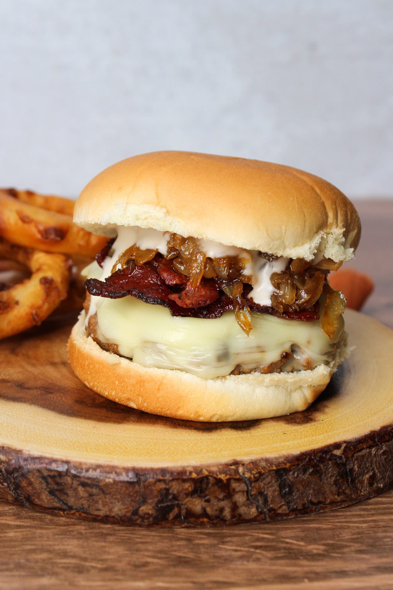 A burger with bacon, cheese, caramelized onions, and garlic aioli.