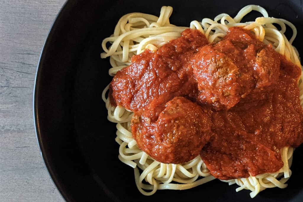 Spaghetti and meatballs in a black bowl