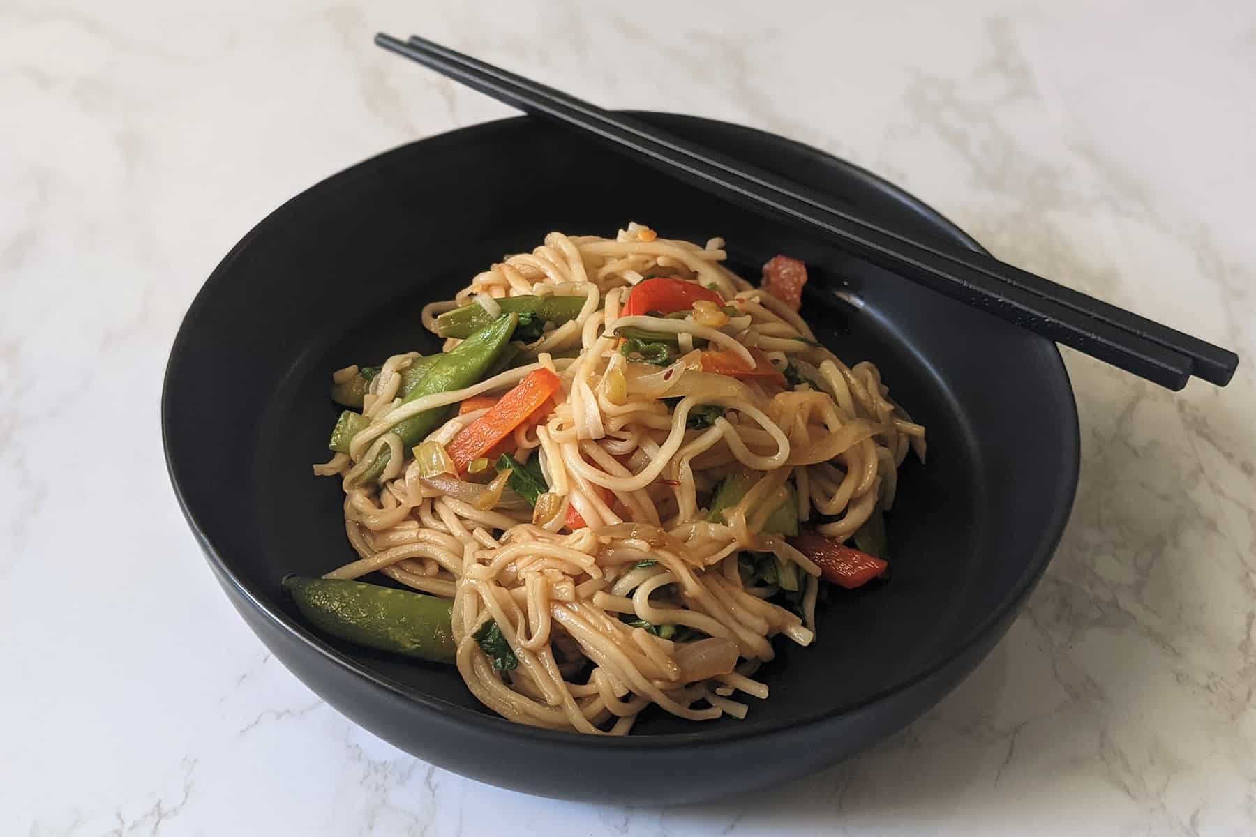 Udon stir fry with vegetables in a serving bowl with chopsticks