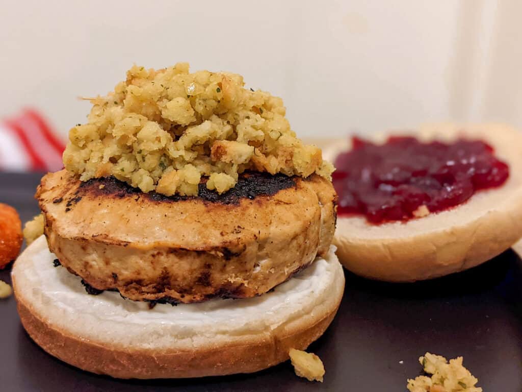 A Thanksgiving turkey burger with stuffing and cranberry sauce on a potato bun