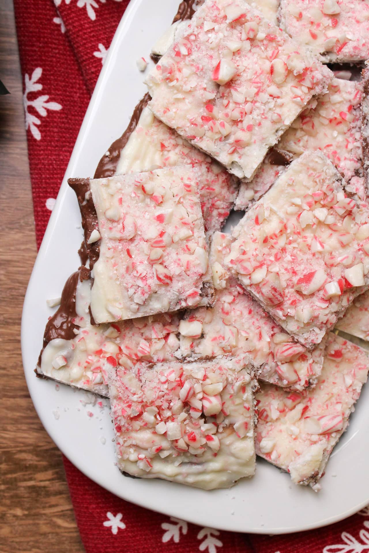 Squares of homemade milk chocolate peppermint bark on a white plate.