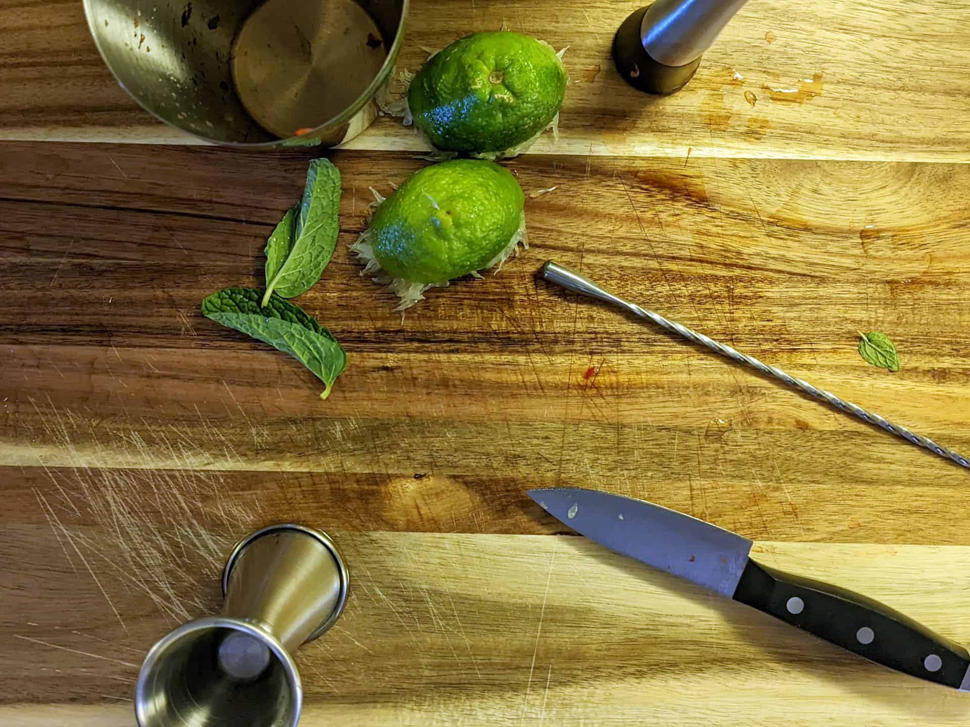 A wooden bar top with ingredients for making mojitos and other cocktails
