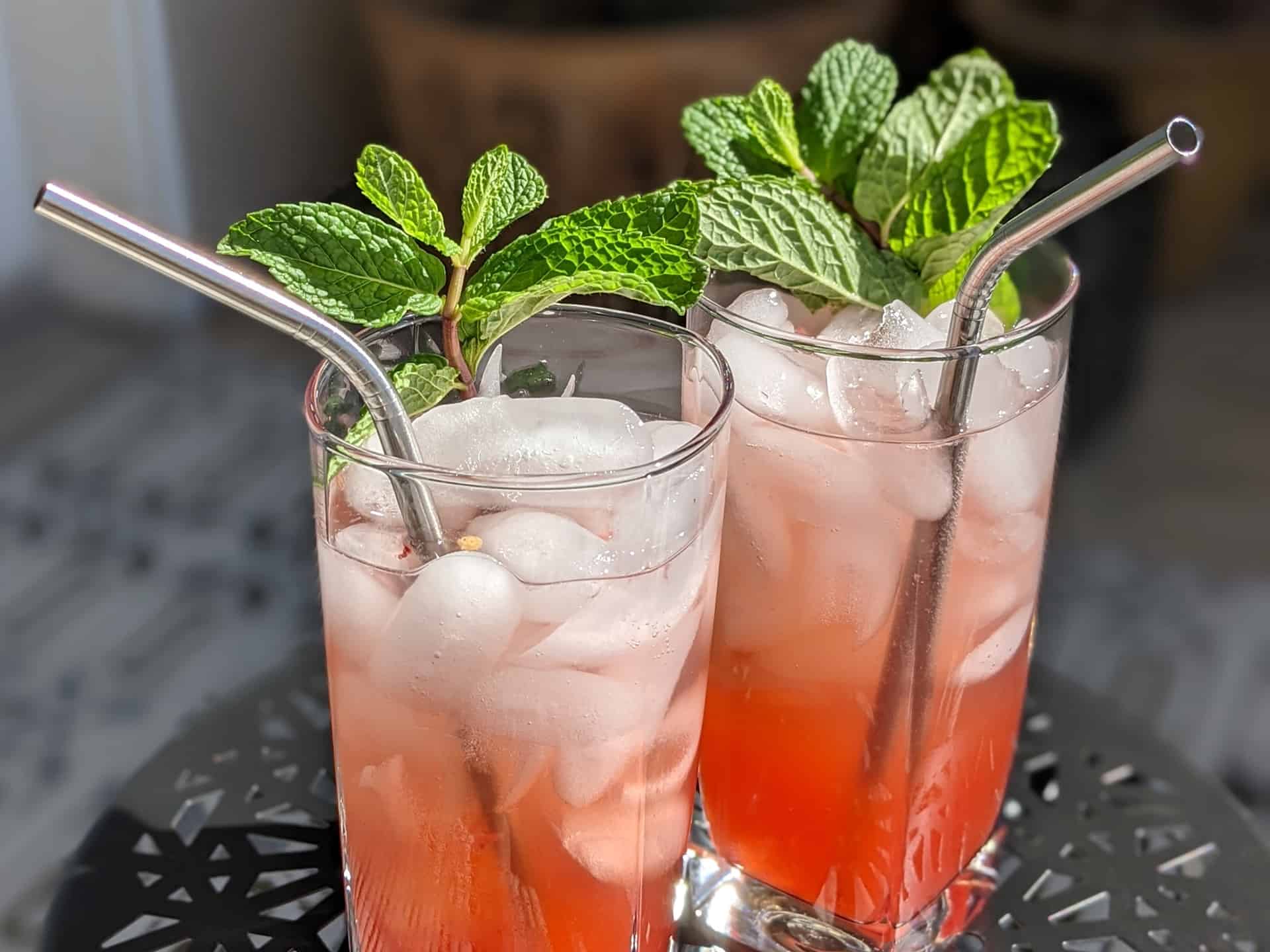 A closeup view of two strawberry jalapeno mojitos garnished with mint sprigs