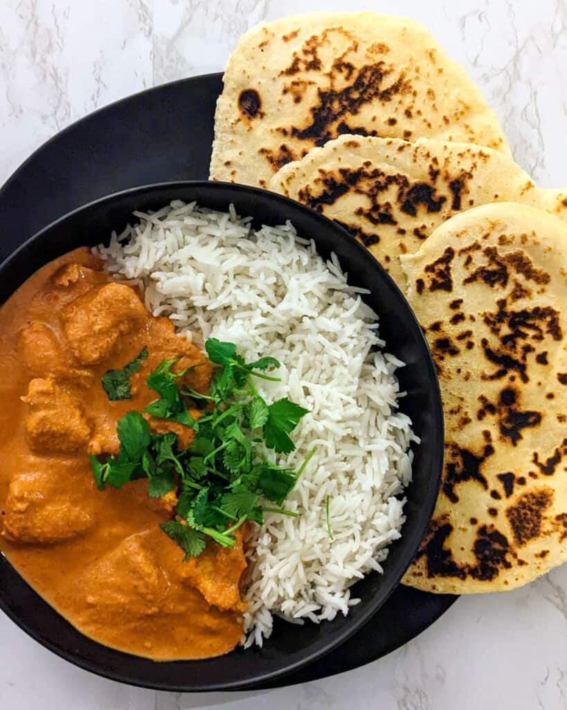 A bowl of homemade chicken tikka masala with a side of naan