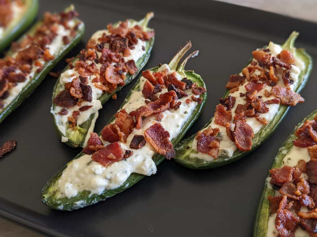 A serving dish of jalapeno popper boats with bacon and garlic and herbs cheese
