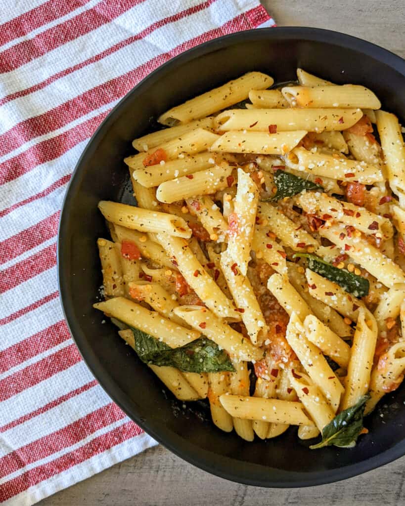 A bowl of tuscan penne pasta with fresh tomatoes, basil, and parmesan cheese