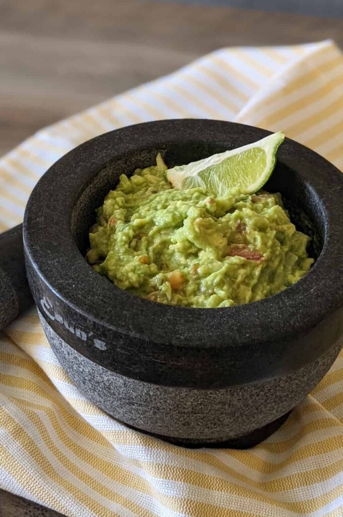 A bowl of fresh guacamole garnished with a lime wedge