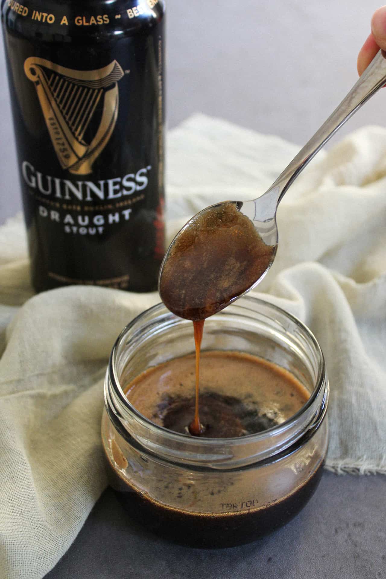 Guinness glaze being scooped from a bowl with a spoon.