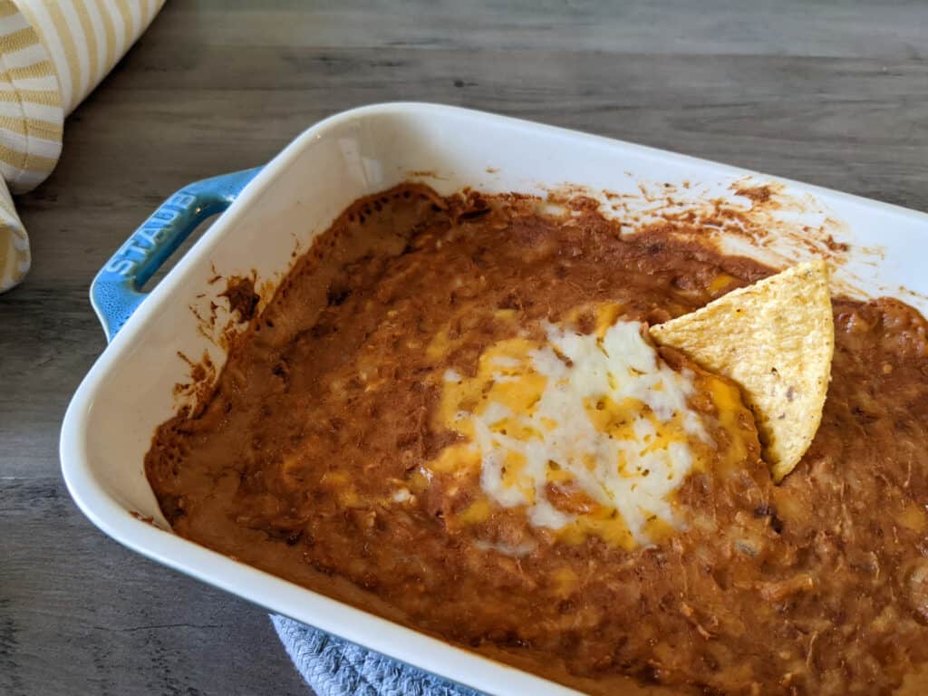 A serving dish of oven-baked bean dip with tortilla chips