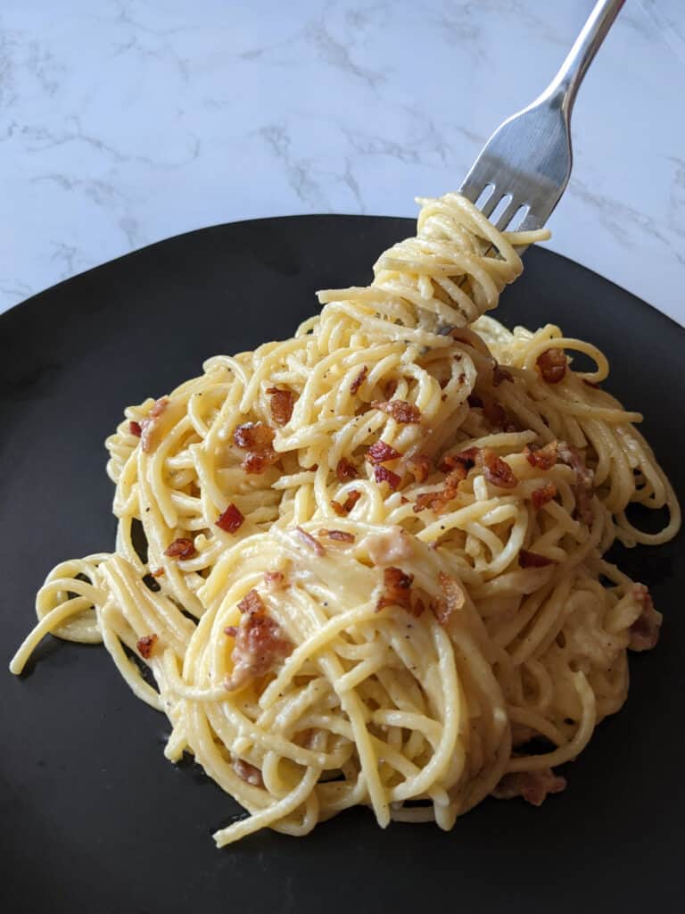 A fork twirling spaghetti carbonara