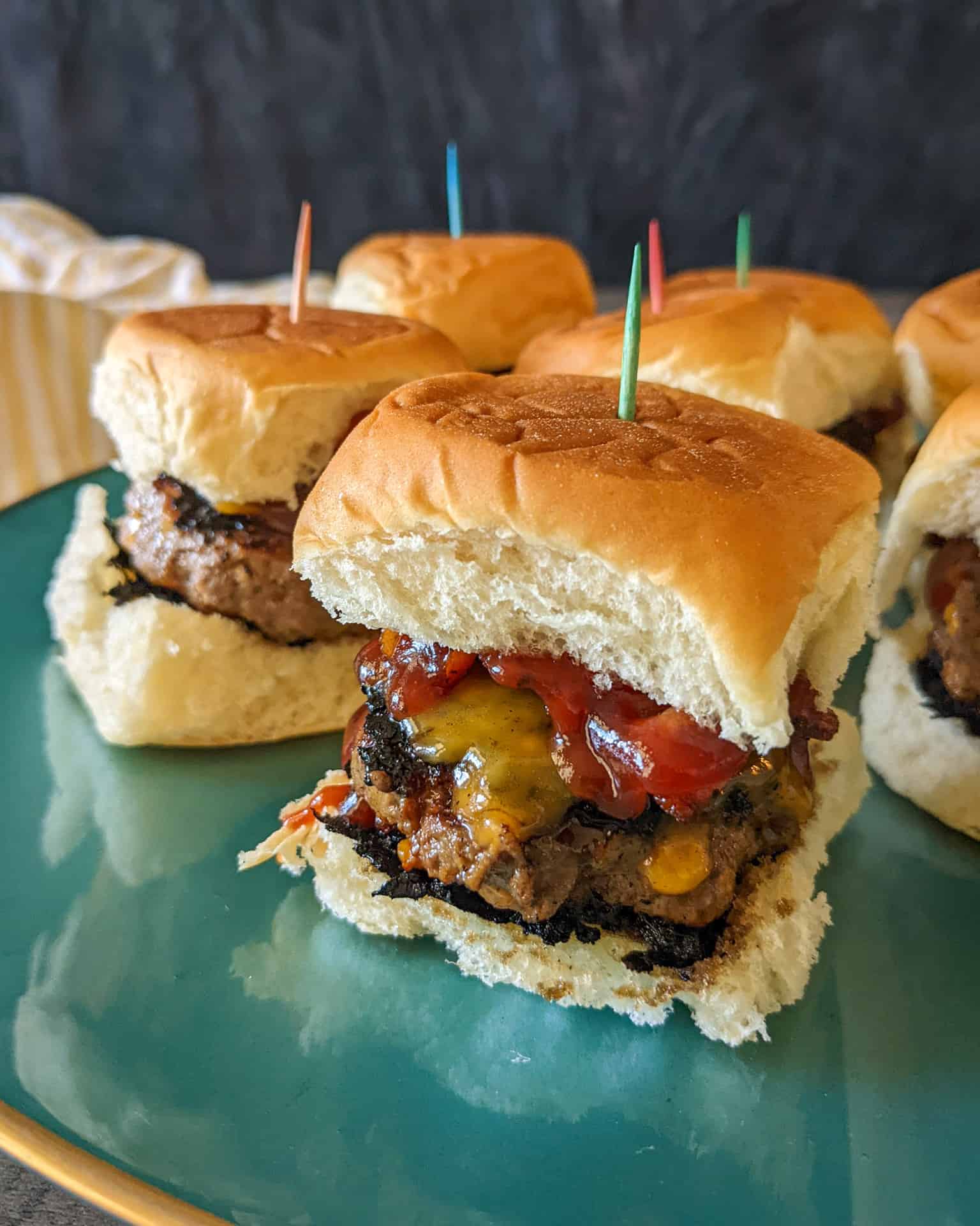 A plate of bacon cheeseburger sliders with bbq sauce