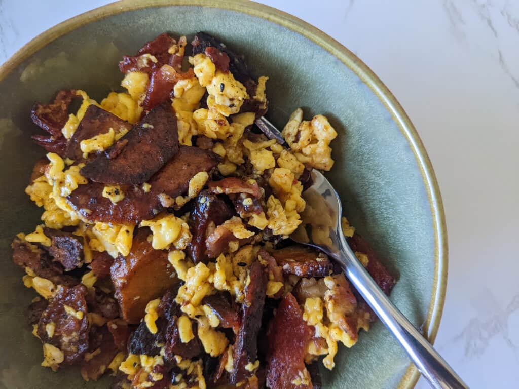 A breakfast scramble with bacon, eggs, and potatoes in a bowl
