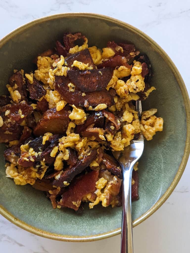 A bowl of breakfast scramble with bacon, eggs, and potatoes