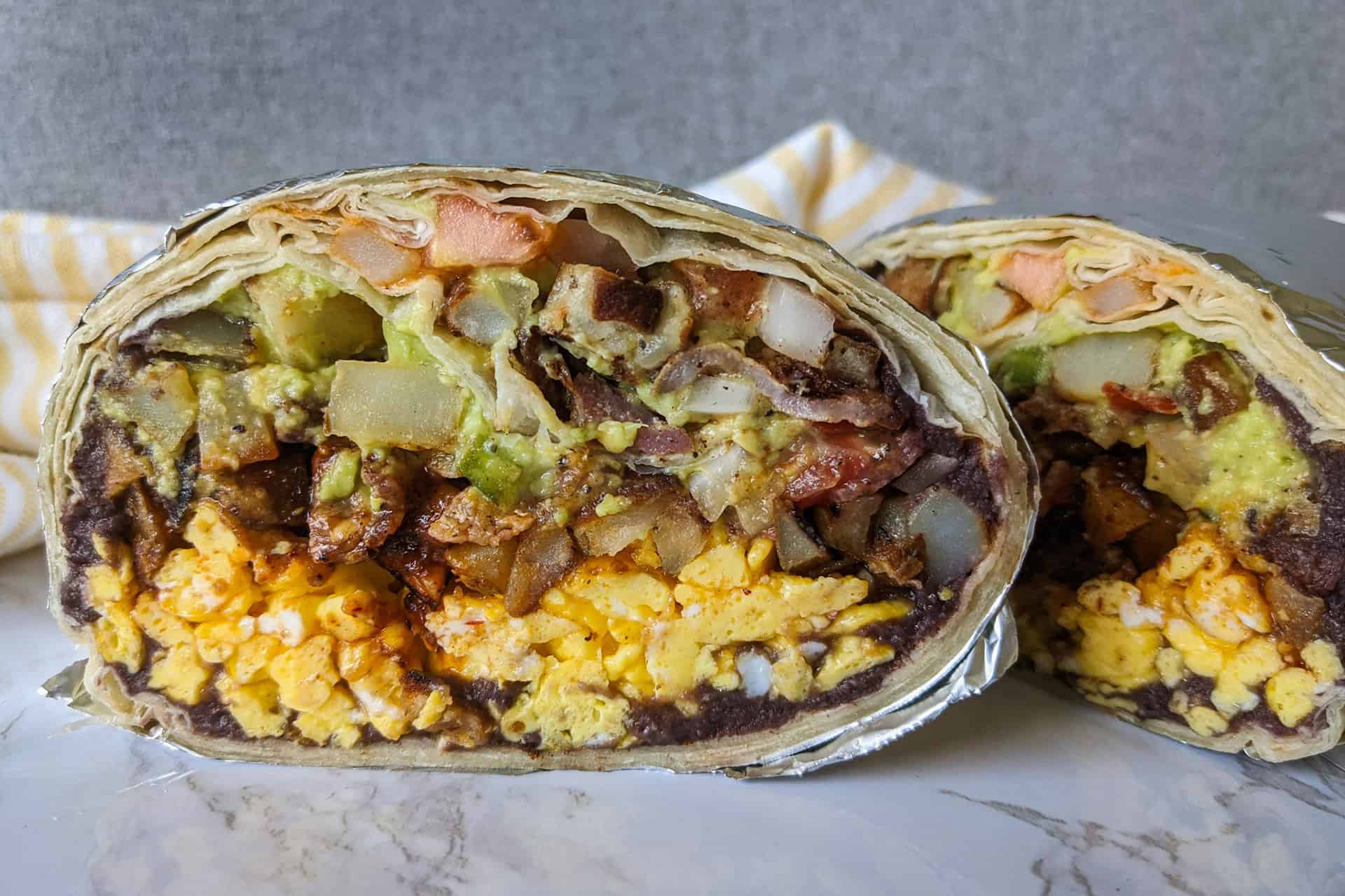 A giant breakfast burrito with eggs, beans, and cheese