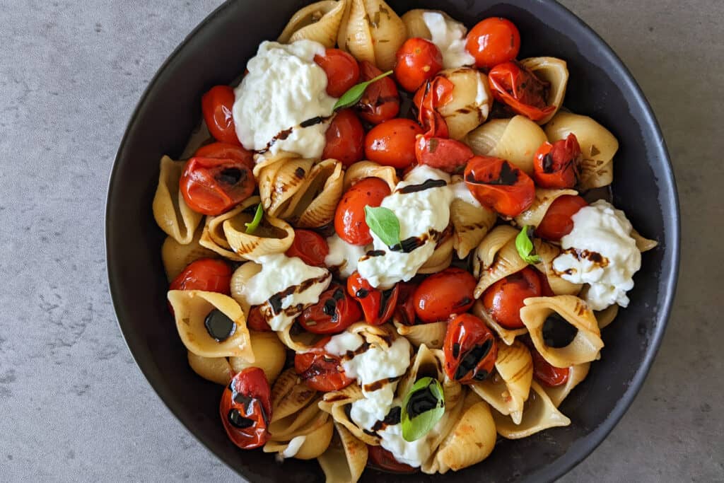 A bowl of burrata pasta with blistered tomatoes and balsamic vinegar