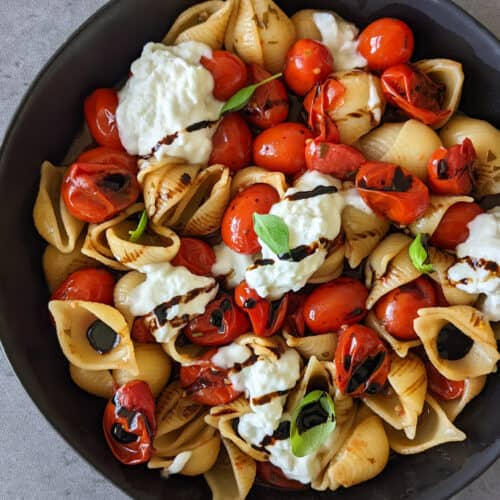 A bowl of burrata pasta with blistered tomatoes and balsamic vinegar
