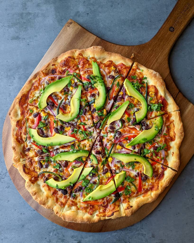 A thin crust veggie pizza served on a wooden pizza peel
