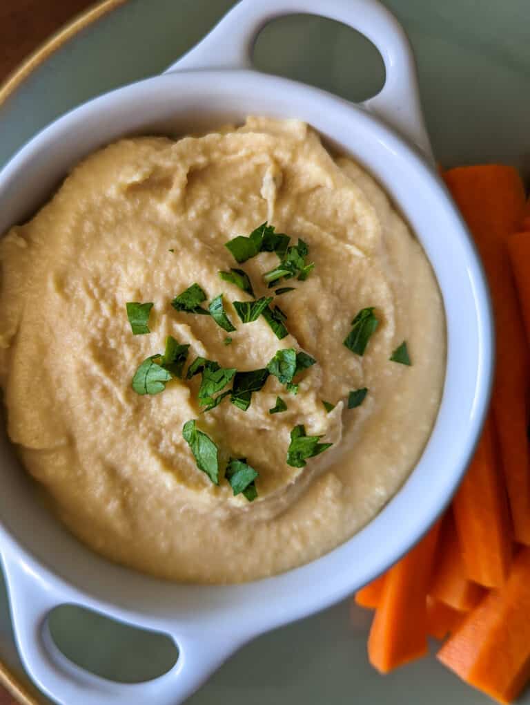 Homemade hummus in a serving dish with carrots