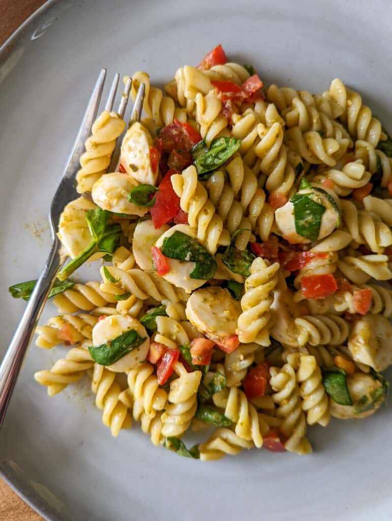 Caprese pesto pasta on a plate with a fork