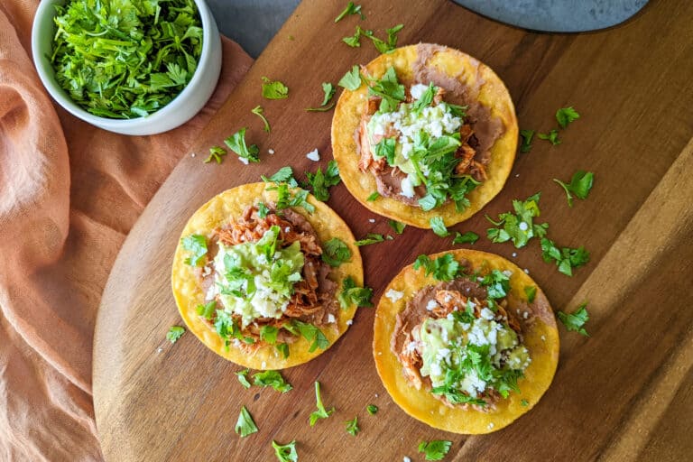 Three chicken tinga tostadas on a serving tray