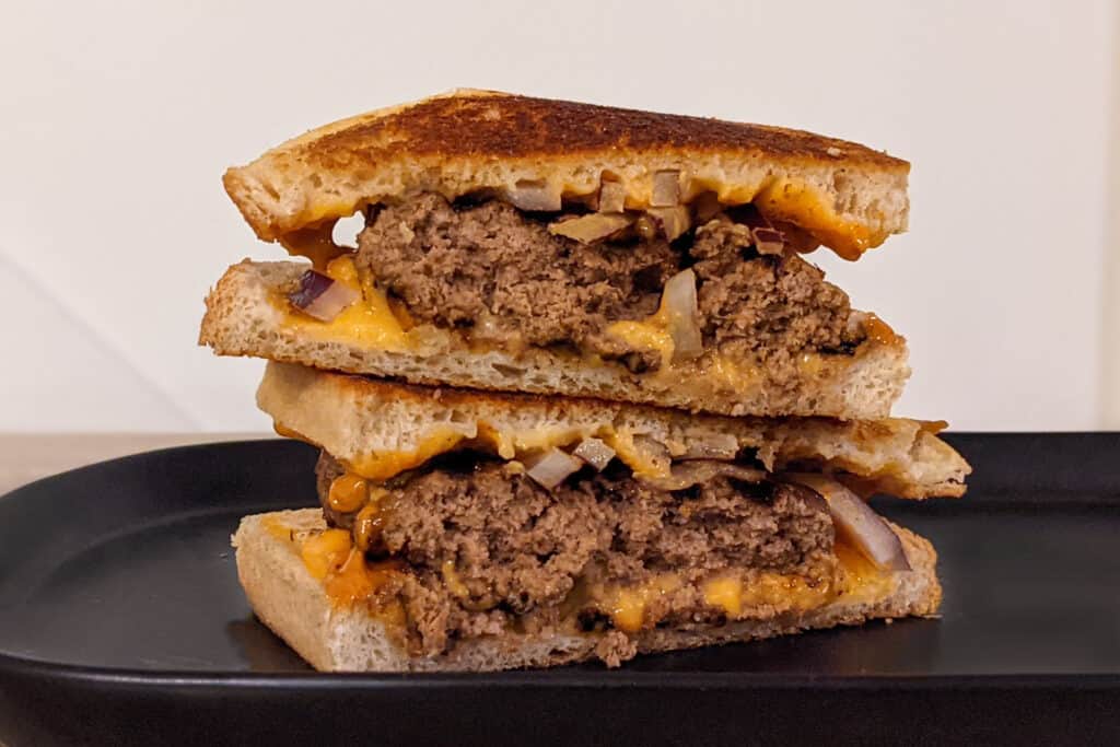 A grilled cheese patty melt burger with red onions and chipotle mayo