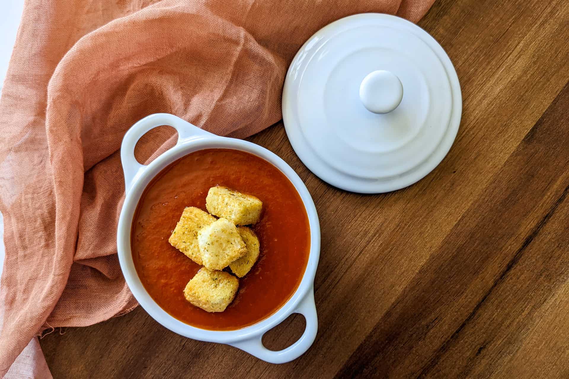 Slow cooker tomato soup in a serving dish with croutons on top