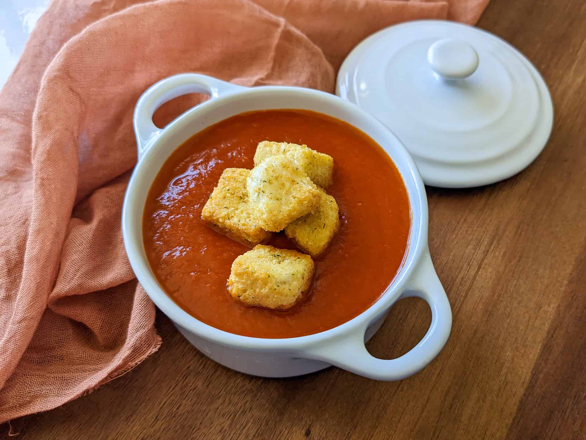 A bowl of creamy tomato soup with croutons