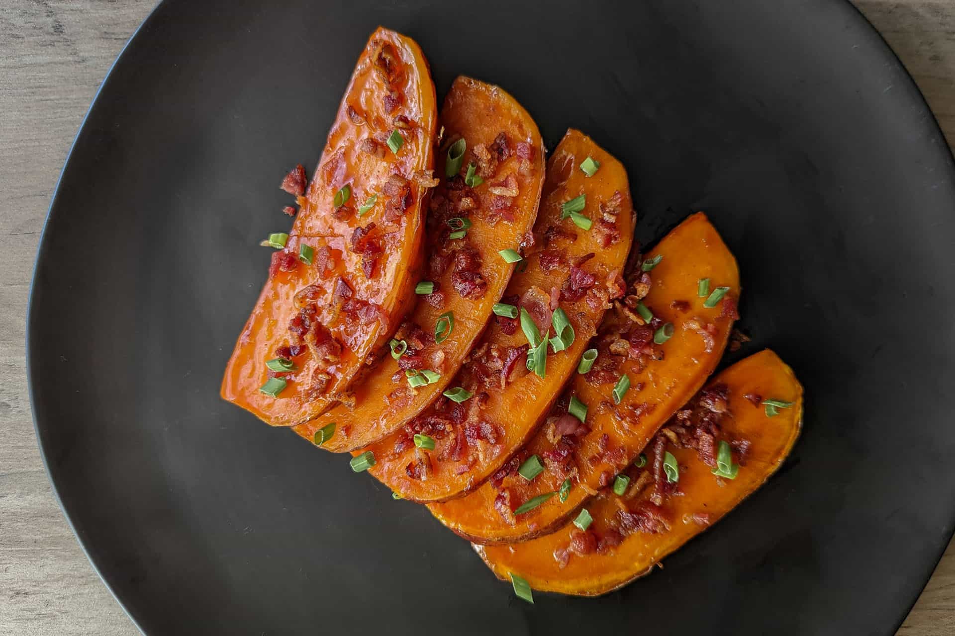Wedges of maple glazed sweet potato topped with bacon and chives