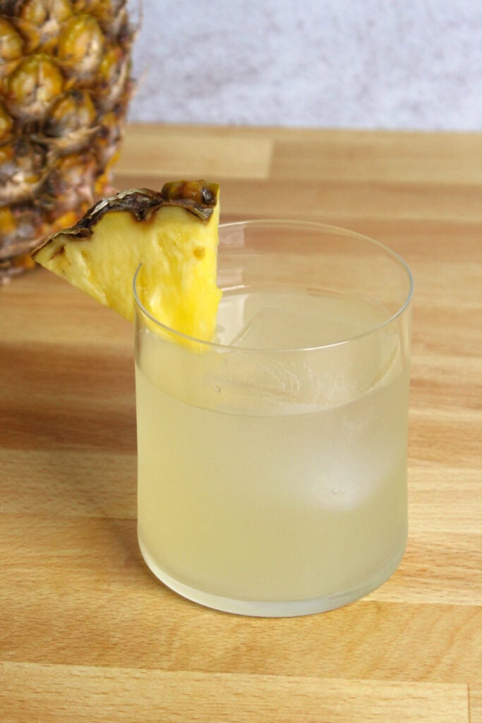 A cocktail garnished with a pineapple wedge.