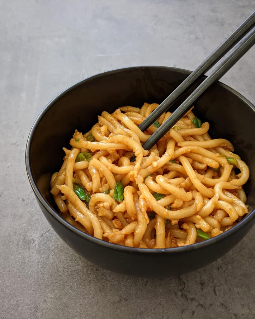 Asian fusion garlic noodles in a bowl with a pair of chopsticks