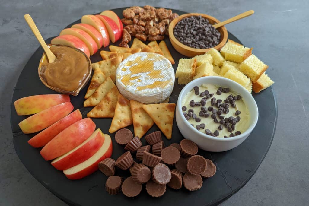 A dessert charcuterie board full of sweets, cheeses, and fall produce