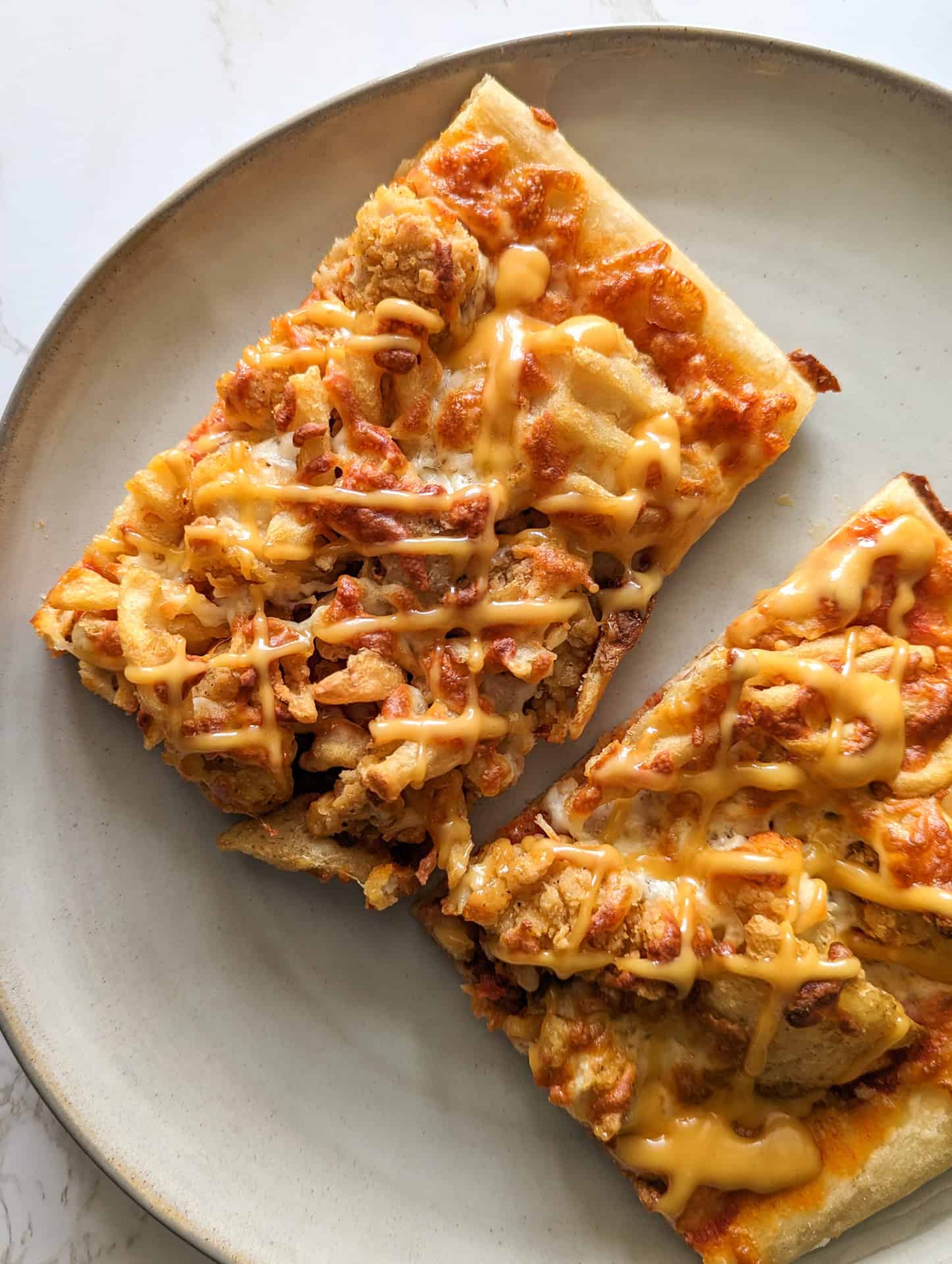 Two square slices of chick-fil-a pizza on a white plate.