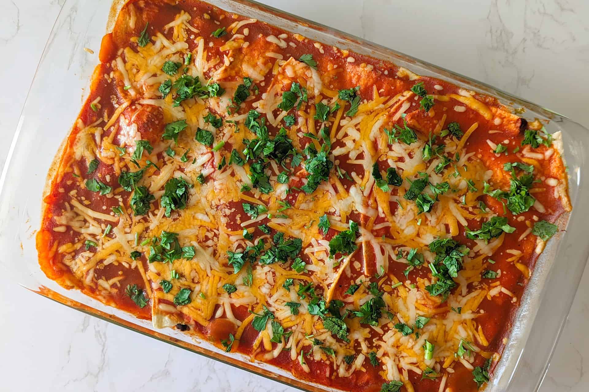 An easy chicken enchilada casserole served in a glass baking dish