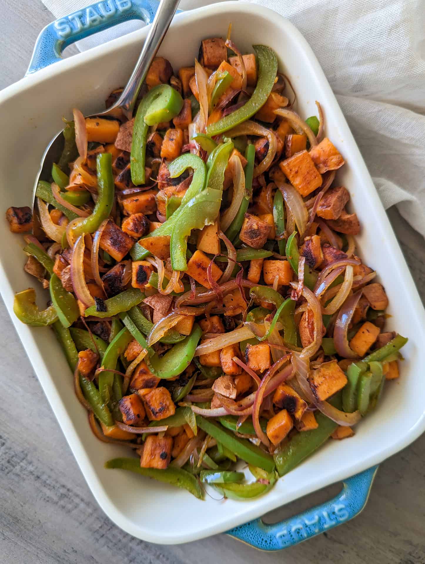 Vegan sweet potato breakfast hash with peppers and onions in a serving dish