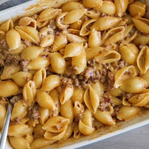 A big batch of cheeseburger mac and cheese in a baking dish with a serving spoon