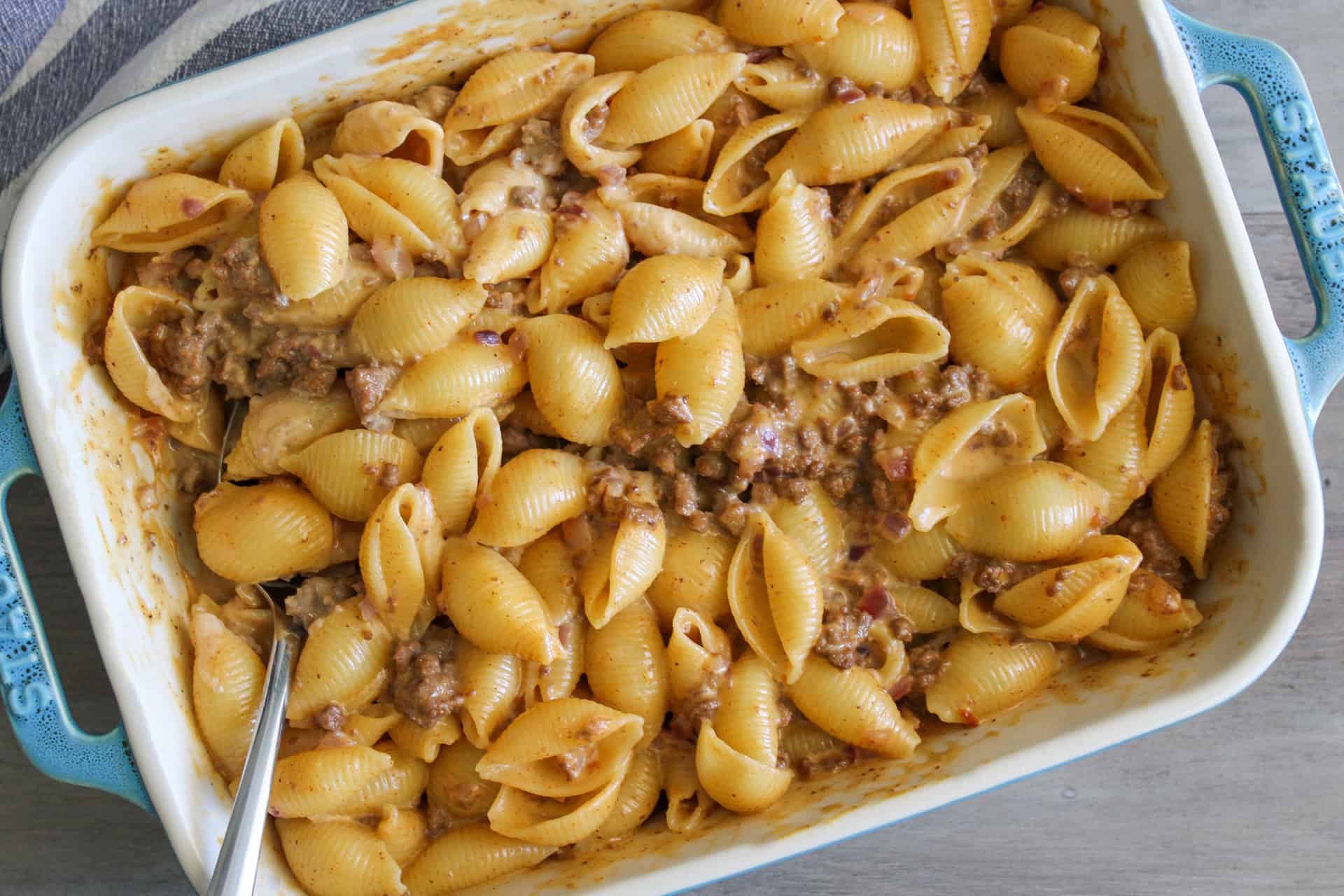 A big batch of cheeseburger mac and cheese in a baking dish with a serving spoon