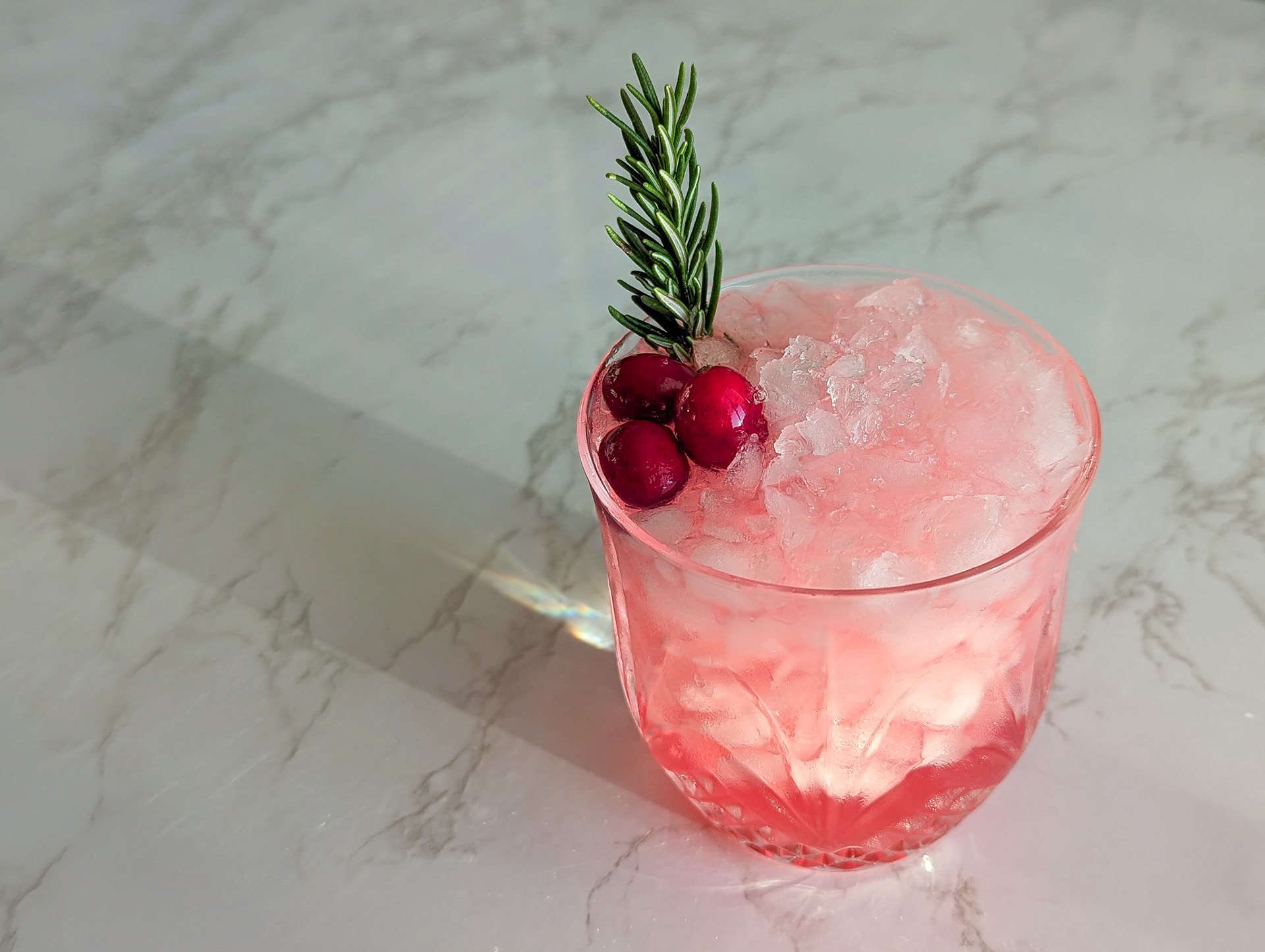A mistletoe mule cocktail made with cranberry juice garnished with cranberries and rosemary