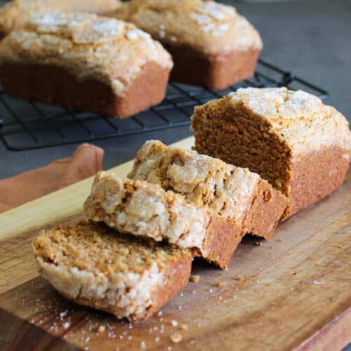 A sweet potato quick bread loaf on a cutting board with a few pieces cut