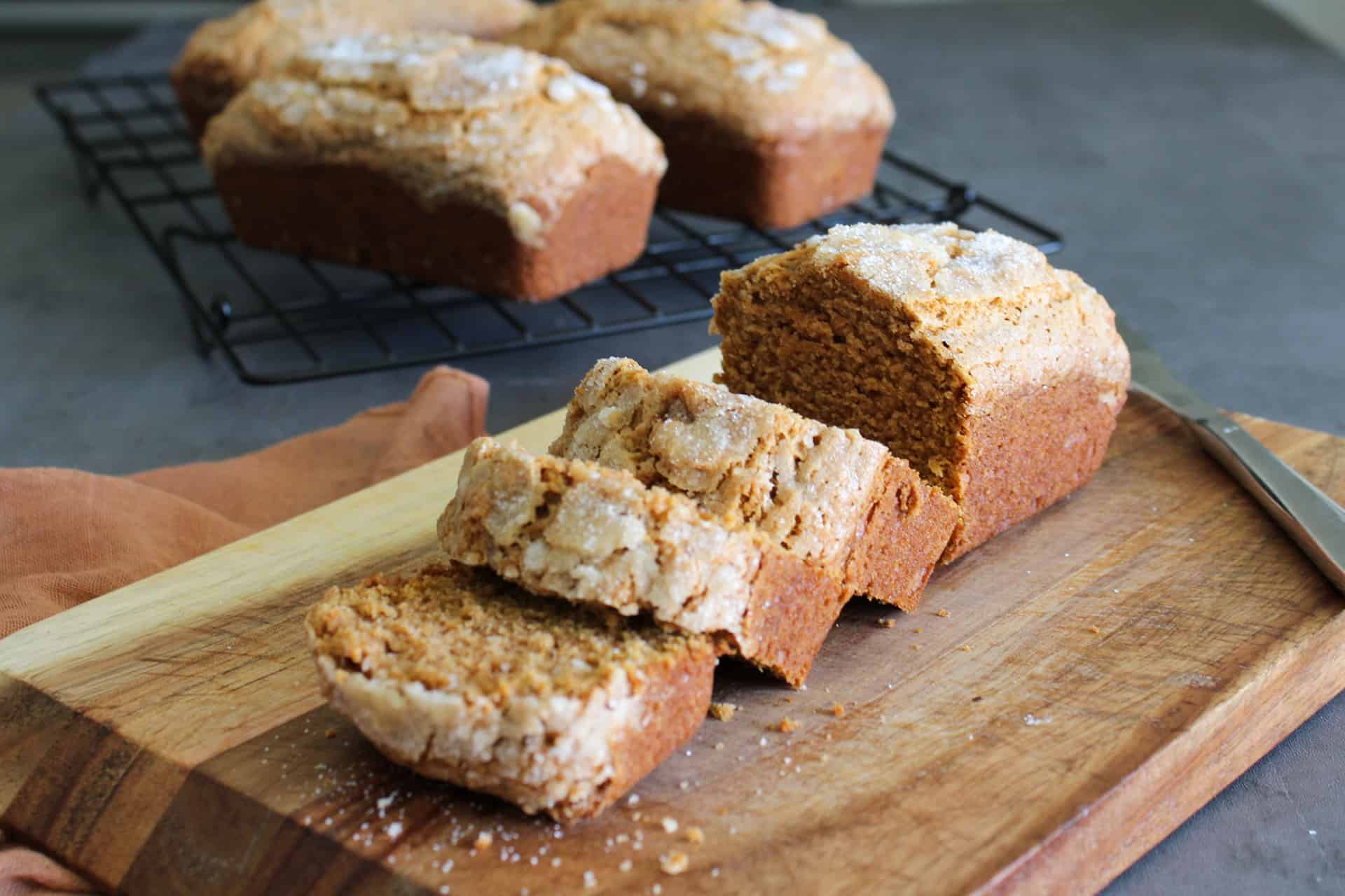A sweet potato quick bread loaf on a cutting board with a few pieces cut