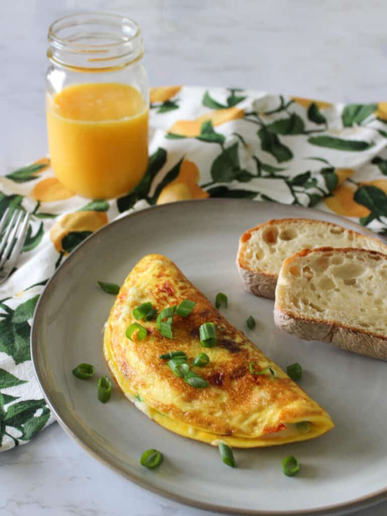 A veggie omelet with a side of toast and a glass of orange juice